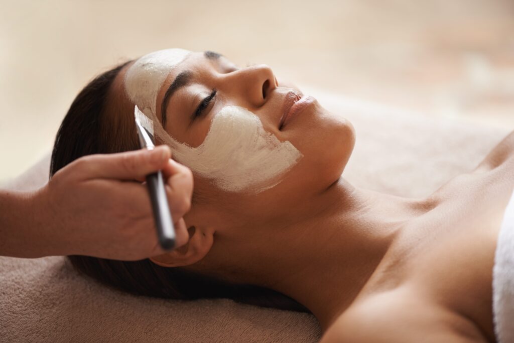 Your skin deserves some pampering. A face mask being applied to a beautiful young woman at a beauty spa.