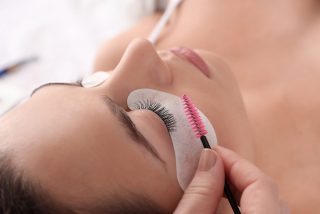 Young woman undergoing eyelash extension procedure in beauty salon, closeup