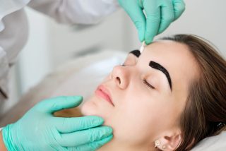 Makeup artist applies paint henna on eyebrows in a beauty salon