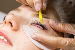 Female face under procedure of eyelashes lamination in beauty salon, closeup